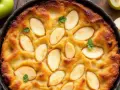 Un délicieux clafoutis aux poires, doré et garni de fines tranches de fruits, prêt à être dégusté.