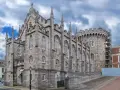Kamienne mury i strzeliste wieże zdobią zamek w Dublinie. Gotycka architektura i chmurne niebo tworzą majestatyczny widok.