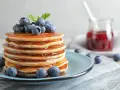 Stos puszystych pancakes polanych syropem, ozdobiony jagodami i miętą. Idealny przepis na pancake na śniadanie.