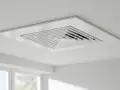 Rejilla cuadrada blanca empotrada en el techo, parte de un sistema de aire centralizado, con un diseño escalonado que dirige el flujo de aire.