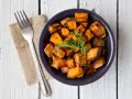 Patate douce air fryer croustillante, garnie d'herbes fraîches, servie dans un bol bleu avec une fourchette.