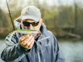 Ein Angler hält einen bunten Gummifisch, ein **big baits hecht** Köder, bereit für den Fang.