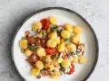 Pyszne makaron gnocchi z pomidorkami, szałwią i orzechami na talerzu.