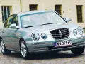 Srebrny Kia Opirus z polskimi tablicami rejestracyjnymi WN 37560 na brukowanej ulicy.