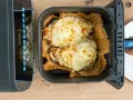 Dos mitades de berenjenas gratinadas con queso fundido, listas para disfrutar, recién salidas de la freidora de aire.