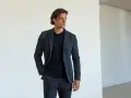 Uomo con giacca e pantaloni grigi, una mano nella tasca laterale del pantalone, mostrando i diversi tipi di tasche pantaloni uomo.