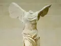 La Victoire de Samothrace, statue grecque antique sans tête, ailes déployées, drapé flottant.