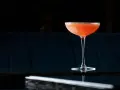 Orzeźwiający el presidente cocktail, z pomarańczowym odcieniem i cukrową obrączką, stoi na błyszczącym blacie.