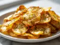Knusprige Kartoffelspalten aus dem Airfryer, bestreut mit Kräutern, auf einem weißen Teller.
