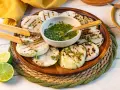 Gegrillte Kohlrabi-Scheiben mit Kräuter-Dressing und Limettenspalten auf einem Holzteller. Ein köstliches Gericht, das Lust auf Kohlrabi grillen macht.