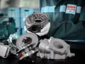 Mechanik w fartuchu Bosch Service prezentuje części turbosprężarki. Rozpoznaj uszkodzona turbina objawy i zgłoś się do serwisu.