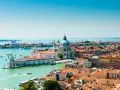 Venezia, con la sua Basilica di Santa Maria della Salute e i canali vibranti, offre infinite curiosità. Le case colorate e i tetti rossi si specchiano sull'acqua.