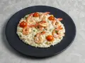 Kremowe risotto z krewetkami i pomidorkami koktajlowymi, posypane natką pietruszki. Idealny przepis na risotto dla każdego.