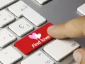 Palec naciska czerwony klawisz z sercami i napisem "Find love", symbolizując bezpieczne randki online.