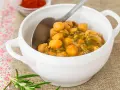 Un tazón blanco lleno de garbanzos con acelgas, un plato reconfortante y nutritivo.