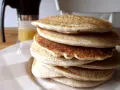 Pila di soffici pancake con farina di avena, dorati e invitanti, pronti per una colazione sana e gustosa.