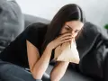 Kobieta z papierową torbą przy ustach, próbująca opanować hiperwentylację.