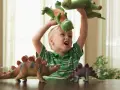 4 letnie dziecko bawi się pluszowymi dinozaurami, wyobrażając sobie prehistoryczną przygodę.