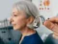 Dłoń prezentuje nowoczesny wzmacniacz słuchu dla seniora, który poprawi jakość życia.