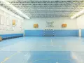 Pusta sala gimnastyczna z niebieską podłogą, boiskiem do koszykówki i piłki ręcznej. Idealne miejsce na zawody sportowe z doskonałym nagłośnieniem sali gimnastycznej.