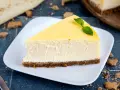 Ein cremiges Stück New York Cheesecake mit einem Keksboden, garniert mit Minze.