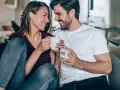 Uśmiechnięta para z kubkami w dłoniach, jakby rozmawiali o horoskopie: byk i ryby.