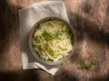 Misternie przygotowana kapusta kiszona w misce, ozdobiona koperkiem i nasionami. Idealna do szybkiego gotowania w szybkowarze.