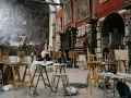 Des chevalets et des toiles dans une **école d'art appliqués**, devant une fresque monumentale et des sculptures. Des étudiants observent une œuvre.