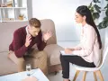 Mężczyzna rozmawia z psychologiem, siedząc na kanapie.
