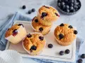 Saftige vegane Blaubeermuffins mit frischen Blaubeeren, auf einem weißen Teller mit blauer Serviette.