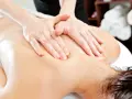 Hands perform a relaxing massage on a person's back, evoking the gentle pressure of shiatsu massage vs deep tissue.