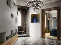 Ingresso di ville liberty moderne con arredi minimalisti, un quadro astratto e un lampadario scenografico.