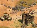 Un ejército avanza en Age of Empires 3, con edificios en llamas y un castillo imponente. ¡Descubre trucos para dominar el campo de batalla!