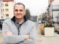 Sebastian Pieńkowski stoi na tle miejskiej ulicy z tramwajami i budynkami.