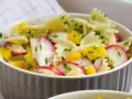 Ein bunter Nudelsalat mit Farfalle, Radieschen und gelben Paprikawürfeln, garniert mit Schnittlauch. Perfekt für den Sommer!