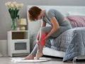 Femme assise sur un lit, se tenant la jambe douloureuse, souffrant de crampes nocturnes.