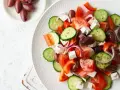 Kolorowa sałatka grecka przepis: świeże pomidory, ogórki, papryka, cebula, oliwki i ser feta.