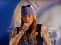 Axl Rose w fioletowej bandanie i czarnej koszulce śpiewa do mikrofonu, jakby dedykował "sweet child o' mine" publiczności.