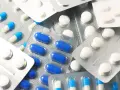 Blistry z białymi i niebiesko-białymi kapsułkami oraz białe tabletki. Wśród nich można znaleźć polopirynę, która pomaga złagodzić ból i gorączkę.