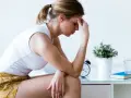 Kobieta z ręką na czole, pogrążona w myślach, może odczuwać objawy zespołu stresu pourazowego.