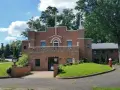 The Holy Face Monastery, a brick building with a large cross, stands on a sunny day.