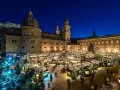 A magical Salzburg Austria Christmas market glows at night, with stalls, trees, and the cathedral creating a festive scene.