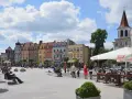 Kolorowy brodnica rynek tętni życiem. Ludzie odpoczywają na ławkach, a kawiarniany ogródek zaprasza do relaksu pod białym parasolem.