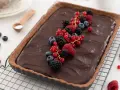 Tarta de chocolate cremosa decorada con frutos rojos frescos: frambuesas, moras, arándanos y grosellas.