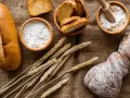 Brot, Getreideähren und Schalen mit Mehl, darunter Vollkornmehl aus Deutschland, liegen auf Jute.