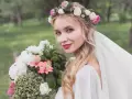 Piękna panna młoda z wiankiem z welonem i bukietem kwiatów w ogrodzie.