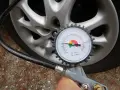 Misurazione della pressione delle gomme auto con manometro. La lancetta indica circa 2.5 bar.