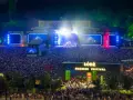 Tłum ludzi na koncercie podczas Łódź Summer Festival 2026. Na scenie gra zespół, a widzowie oświetlają teren telefonami.