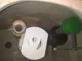Insidan av en toalettcistern med en Gustavsberg Nordic 2002-mekanism. Vatten rinner ner från flottören.