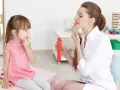 Terapeutka pomaga dziecku 3 lata nie mówi ćwiczyć artykulację. Dziewczynka uważnie słucha, naśladując ruchy ust.